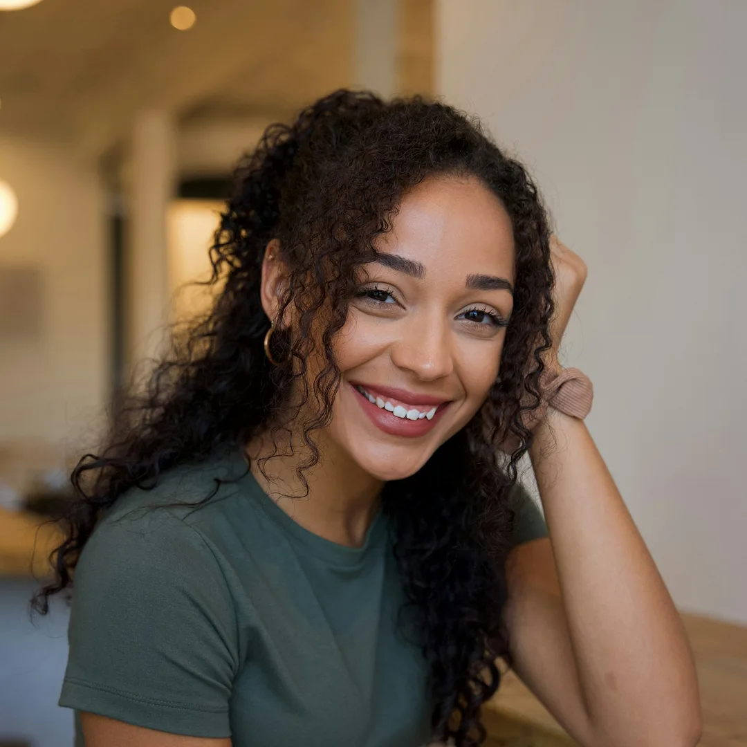 A woman with curly hair smiling at home